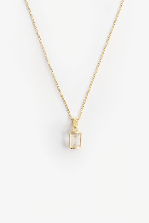 hourglass shaped pendant with two cubic zirconia diamond shapes at either end on a gold chain